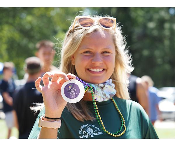 Student holing up necklace smiling.