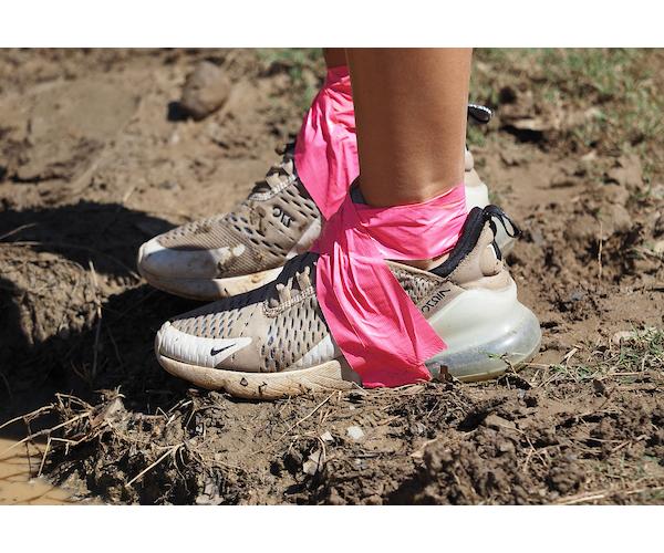 Tennis shoes with pink ribbon tied around legs.